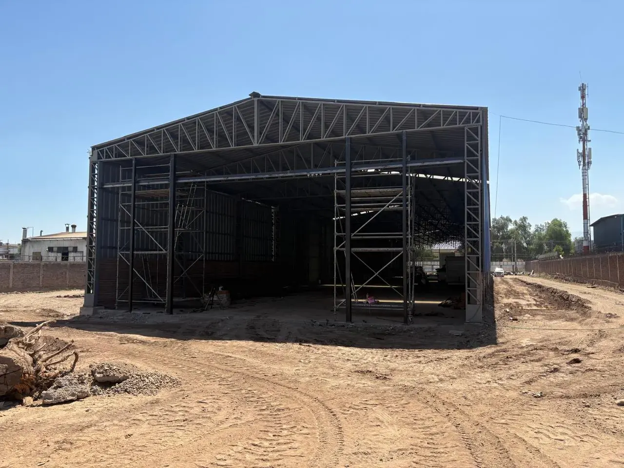 Estructura de galpón metálico en construcción sobre terreno, obra de IKKIO SERVICES