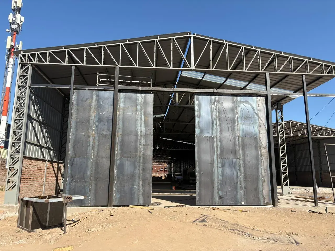 Galpón metálico con estructura de cerchas y portones metálicos, obra de IKKIO SERVICES