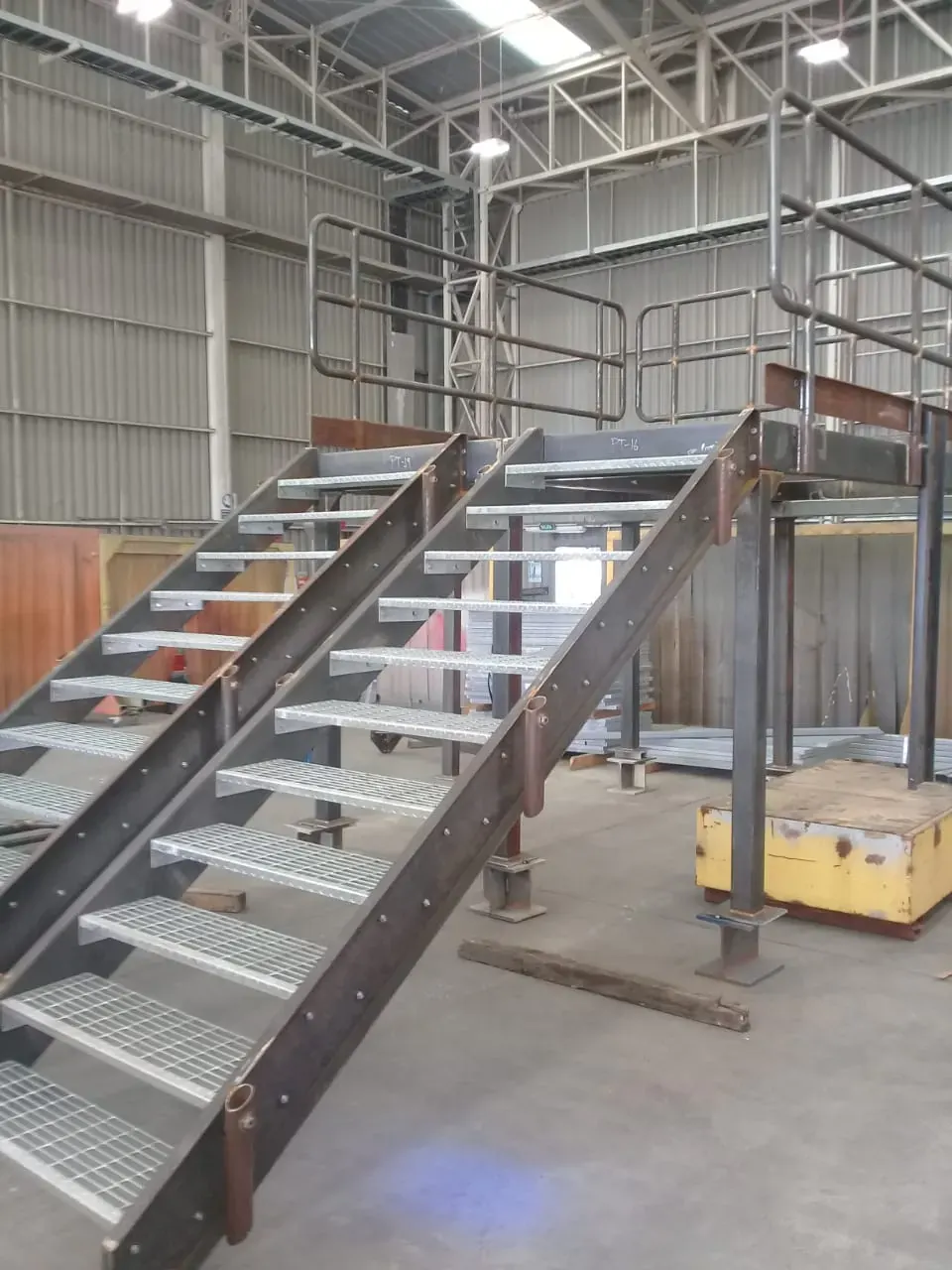 Escalera metálica industrial y estructura de mezzanine fabricada por IKKIO SERVICES en galpón industrial